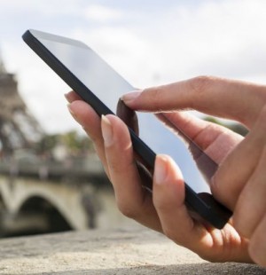 Woman in Paris using her cell phone in front of Eiffel Tower
