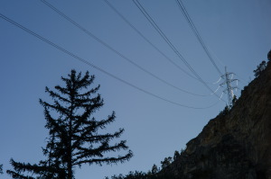 Elektrizitaet-Strommasten auf Felsen mit Tanne